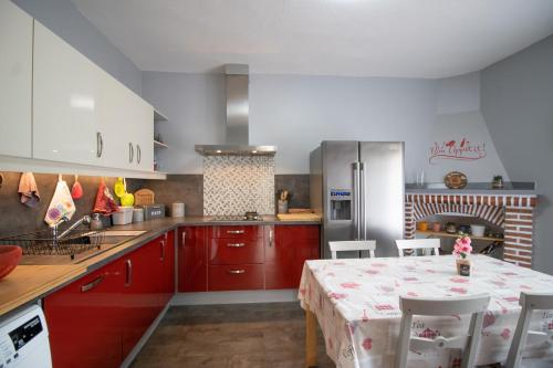 - une cuisine avec des placards rouges, une table et une cuisinière dans l'établissement Au Pont De Tuarelli, Ludique, Fango, à Manso