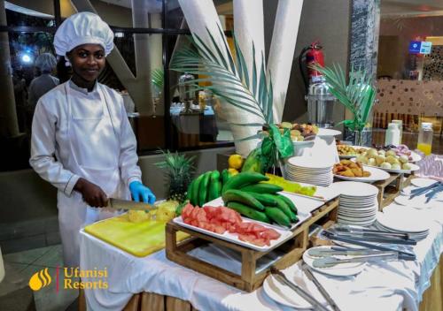 a woman standing in a kitchen preparing food at Ufanisi Resort - Kisii in Kisii