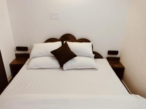 a bed with white sheets and black pillows at RKs HOME STAY in Shillong