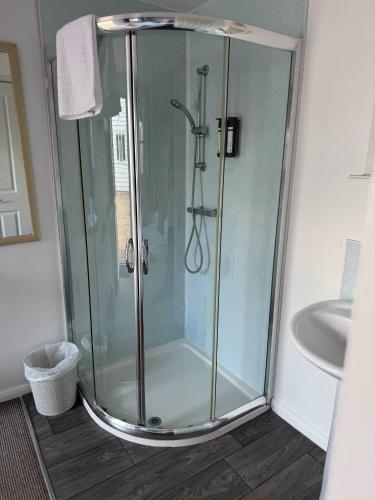 a shower with a glass door in a bathroom at Cabin 6 in Bradwell on Sea