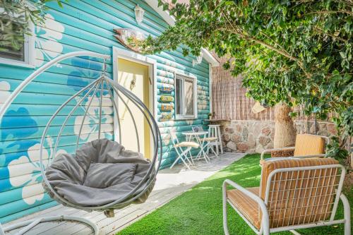 a porch with a swing next to a blue house at דאוס האוס - דירות אירוח מודרניות ושקטות in Eilat