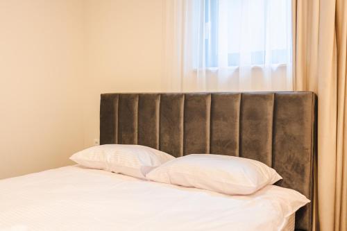 1 cama con sábanas blancas y 2 almohadas en Cometei Residence Apartments 2, en Cluj-Napoca