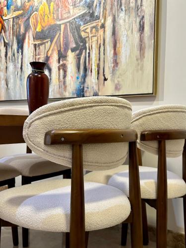 two chairs and a table with a vase and a painting at شقة فندقية بالشيخ زايد Zed residense in Cairo