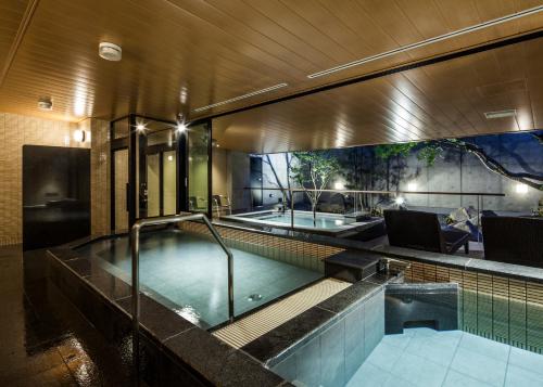 uma piscina com uma banheira de hidromassagem num edifício em Fukui Manten Hotel Ekimae em Fukui