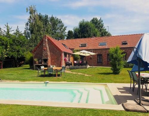 a house with a swimming pool in front of a building at La Vendegeoise - Gîte chaleureux 10P chez l'habitant - Jardin- Piscine ext chauffée partagée de mai à septembre in Vendegies-au-Bois