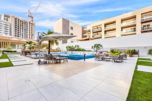 an outdoor patio with tables and chairs and a pool at FIRST CLASS Studio Luxe & Cozy Vibes in Dubai