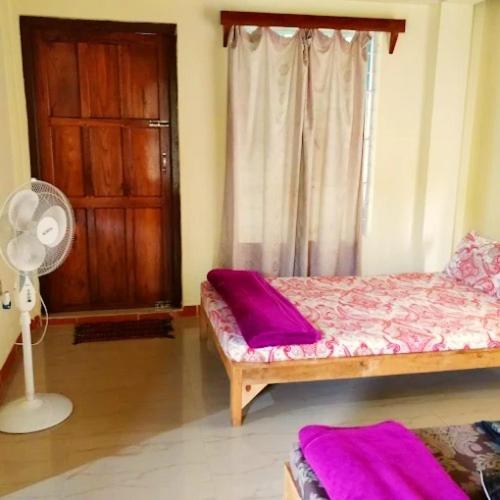 a room with a bed and a window with a fan at Streamside Guest House in Mawlynnong