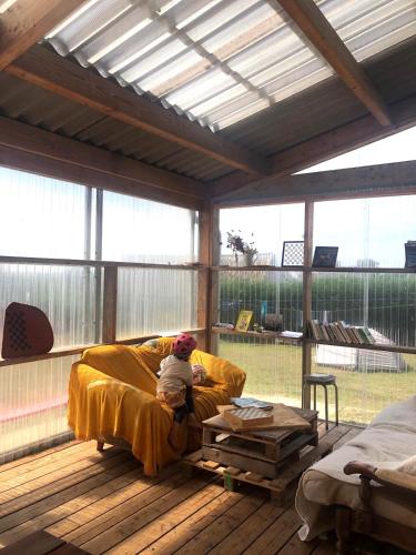 a child sitting on a couch in a covered porch at Ostal Île de Batz - Auberge de jeunesse in Île de Batz
