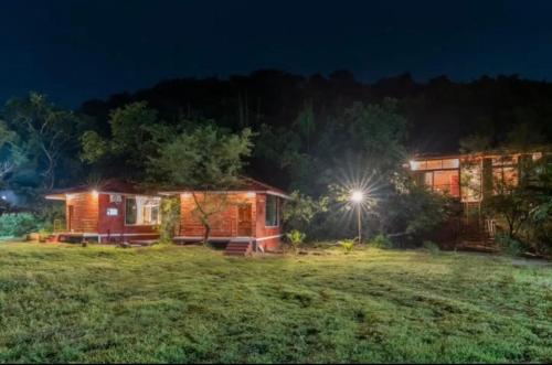 a house in a field at night with a light at Leafyden Forest Cottages in Talekhār