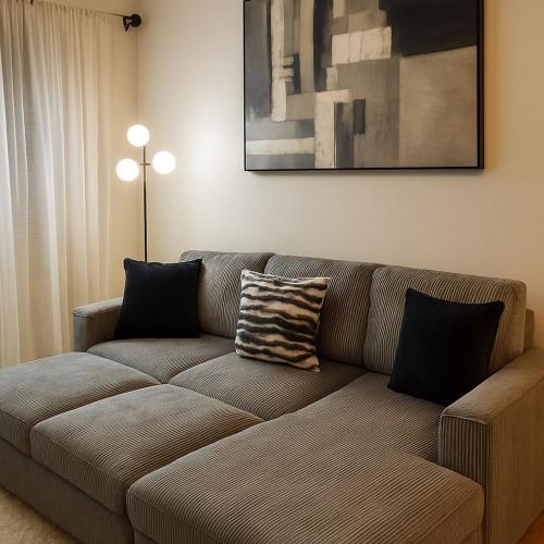 a brown couch in a living room with a painting at 10 Min to NYC Quiet 1BR Flash Deal June 22 to 25 in Weehawken