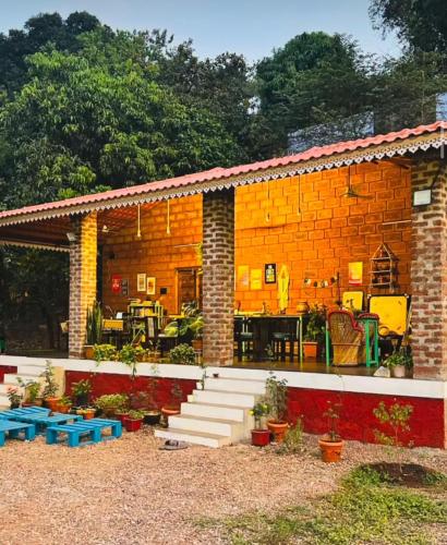 a small brick building with stairs and tables and plants at Leafyden Forest Cottages in Talekhār