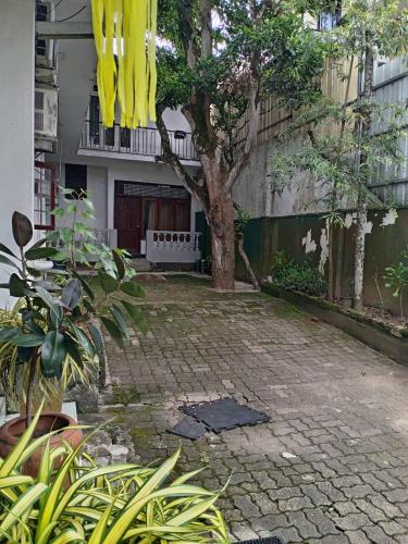 a brick courtyard with a tree and a building at The Sanhida Guest House Colombo in Nugegoda