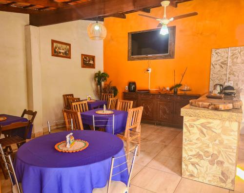 a dining room with two purple tables and a tv at POUSADA MANACÁ DA SERRA in Vargem Bonita