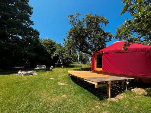 a red tent with a wooden platform in a field at Löwenhof Jurte in Wald