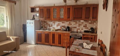 a kitchen with wooden cabinets and a white refrigerator at Nardi Guesthouse in Ksamil