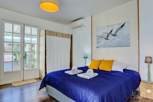 a bedroom with a blue bed with two towels on it at VILLA KELOHA - Luxueuse villa créole in Étang-Salé les Bains