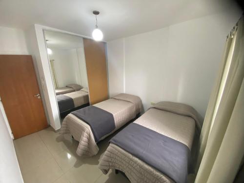 ein kleines Zimmer mit zwei Betten und einem Spiegel in der Unterkunft Departamento sobre AVENIDA con BALCON in Santiago del Estero