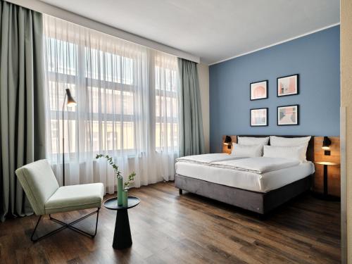 a bedroom with blue walls and a bed and a chair at Garner Hotel Berlin - Schöneberg by IHG in Berlin
