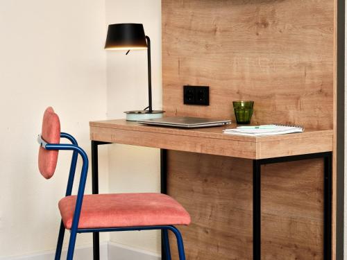 a desk with a laptop and a red chair at Garner Hotel Berlin - Schöneberg by IHG in Berlin