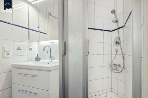 a white bathroom with a sink and a shower at Seeblick Leuchtturm in Ostseebad Koserow