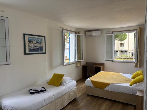 Un dormitorio con dos camas y dos ventanas. en Hotel Bellevue, en Saint-Florent