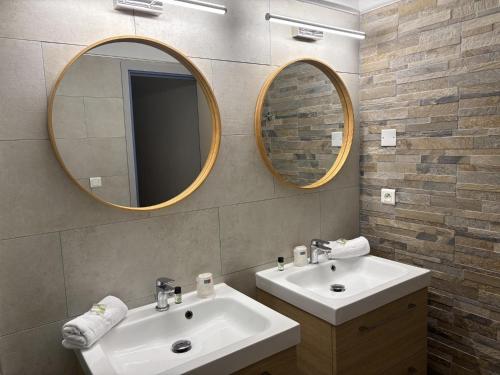 un baño con dos lavabos y dos espejos en Hotel Bellevue, en Saint-Florent