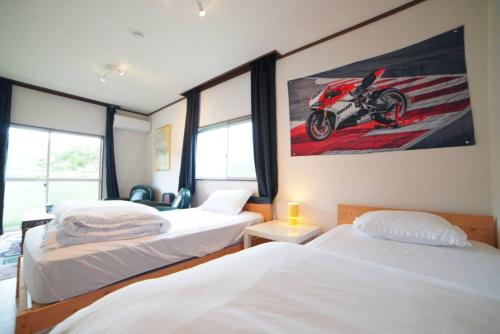 two beds in a room with a motorcycle on the wall at 【芦ノ湖徒歩10分＆バス停1分】一棟貸切最大14人 大人數BBQ可能 パーティ 『ROUTE99』 in Moto-hakone