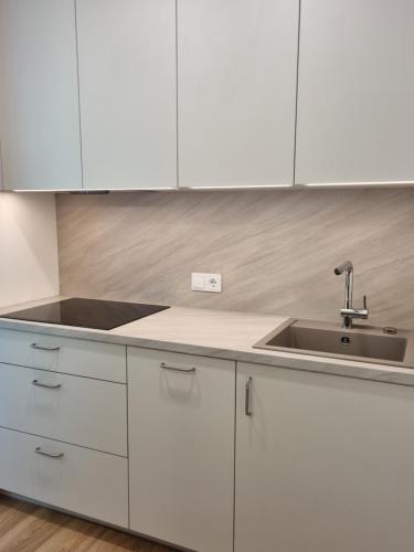 a kitchen with white cabinets and a sink at Apartamentų nuoma Juodkrantėje in Juodkrantė