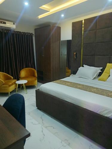 a hotel room with a large bed and a chair at Elnido by Kdove in Ikeja
