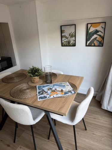 - une table à manger avec 2 chaises blanches et une table dans l'établissement Sabl'Appart Gare, à Les Sables-dʼOlonne