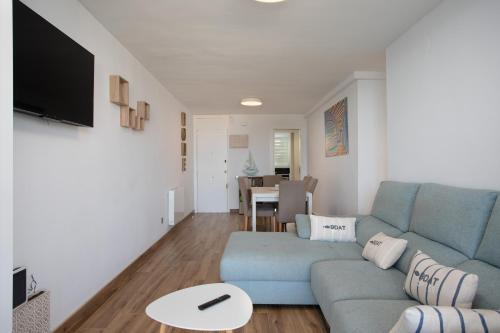 ein Wohnzimmer mit einem blauen Sofa und einem Tisch in der Unterkunft Apartament gran amb vistes al mar, piscina i pàrquing in Calella de Palafrugell