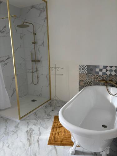 a bathroom with a white tub and a shower at Le Jardin de la Guionie in Rieupeyroux