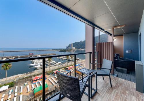 a room with a balcony with a view of a harbor at LiVEMAX RESORT Atami Sea Front in Atami