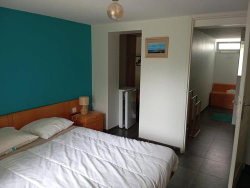 a bedroom with a white bed and a blue wall at Helen in Bergerac