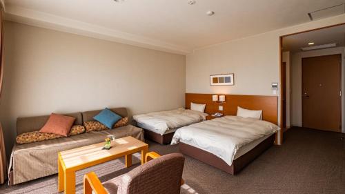 a hotel room with two beds and a couch at LiVEMAX Resort Izu Kogen Terrace & Spa in Ito