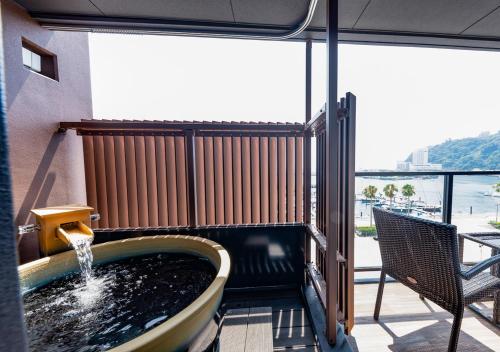 a hot tub in a balcony with a view of the ocean at LiVEMAX RESORT Atami Sea Front in Atami