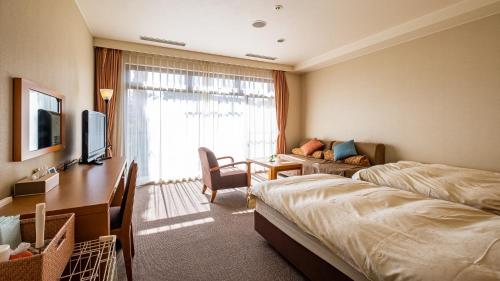 a hotel room with two beds and a desk and a television at LiVEMAX Resort Izu Kogen Terrace & Spa in Ito