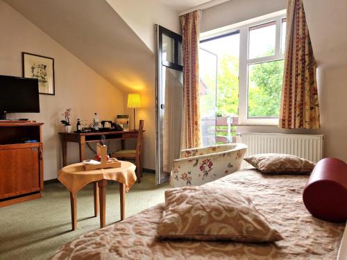 a bedroom with a bed and a window and a tub at Hotel Zum Stein Wellness & Genuss Resort in Oranienbaum-Wörlitz