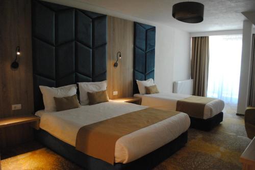 a hotel room with two beds and a window at Nedei Hotel&Spa Transalpina in Martinie