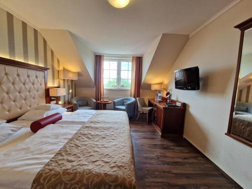 a hotel room with a large bed and a television at Hotel Zum Stein Wellness & Genuss Resort in Oranienbaum-Wörlitz