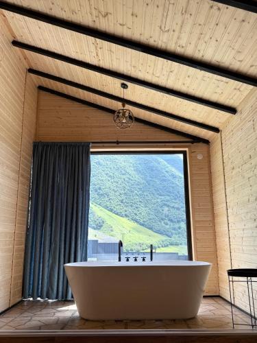 a large tub in a room with a large window at Kazbegi Inn Cottages in Stepantsminda