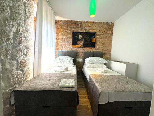 two beds in a room with a brick wall at Rooms Malo more Trogir in Trogir