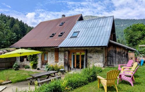 a house with chairs and a table and an umbrella at Au Chalet Du Planolet in Le Massot