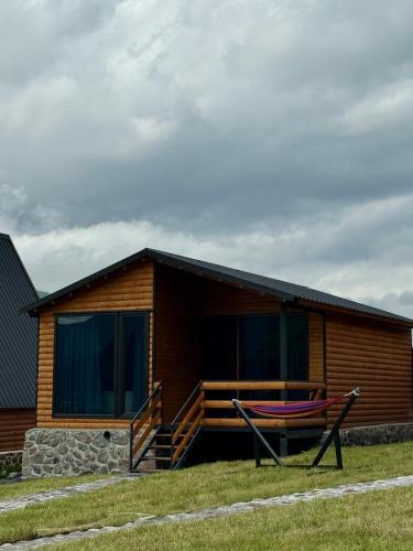 a log cabin with a hammock in front of it at Kazbegi Inn Cottages in Stepantsminda