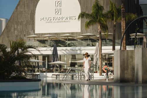a woman standing next to a pool in a building at Plus Fariones Suite Hotel in Puerto del Carmen