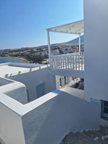 a white building with a balcony on top of it at Paros Carmel studio-apartment in Logaras