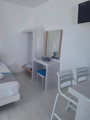 a bedroom with a bed and a desk and a mirror at Paros Carmel studio-apartment in Logaras