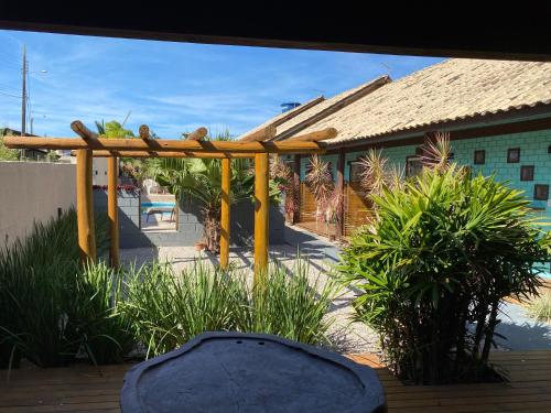 a patio with a wooden pergola and a house at Pousada Hanalie by Easy Hotéis in Praia do Rosa