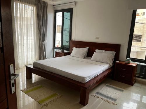 una camera da letto con un letto con lenzuola bianche e finestre di Cocon coloré a Dakar