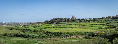 a green hill with a tower on top of it at AX The Heights Residences - Adults Only in Ħal-Bajjada
